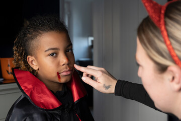 Close-up of woman applying artificial blood in sons face for Halloween