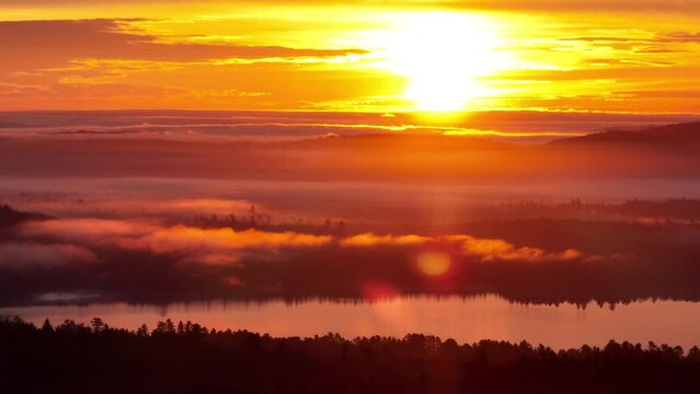 Golden hour sunrise burning through morning fog on lake