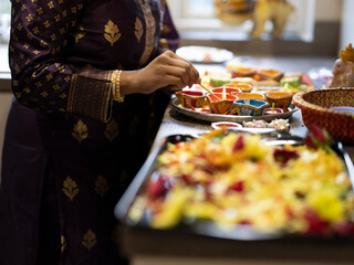 Woman preparing sweet snacks and diyas for Diwali celebration - obrazy, fototapety, plakaty