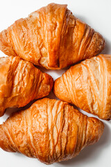 Gold fresh croissants close-up on a white background. Soft pastries for breakfast. Crispy dough in butter. Creative bakery design