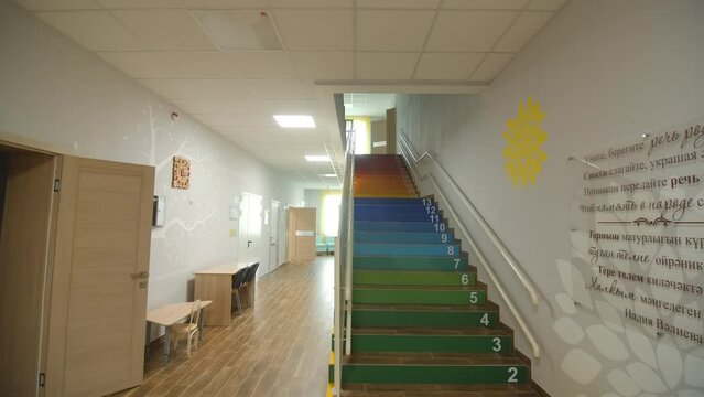 Funny rainbow staircase with digits numeration in light empty kindergarten hallway. Primary school interior design ideas