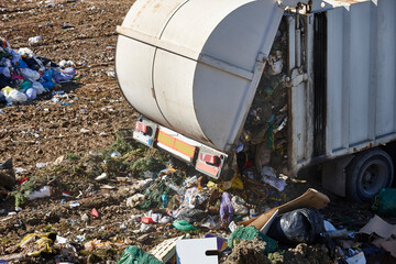 Naklejka premium Truck unloading garbage on an open air dump. Waste treatment