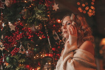 Portrait of millennial candid authentic lady in knit beige sweater in dreamy pose alone at Xmas tree