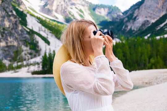 Attractive young woman taking photos of mountains and Lake Braies, Italy.
