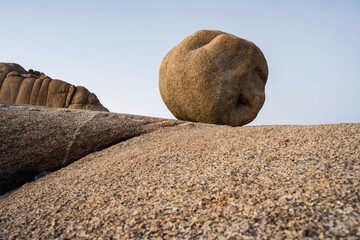Fototapeta na wymiar An almost circular rock lies like a ball on a rock plateau against a blue sky.