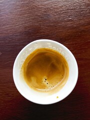 a glass of coffee stands on a wooden table.