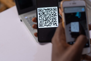 a black man scanning a QR code on a phone with another phone