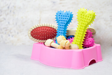 Pet food trays and pet supplies such as plastic bones, hair combs are placed in a pink food tray