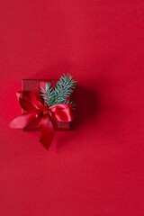 Festive red gift box with fir branches, on a red background. Christmas and New Year concept, holidays, copy space.