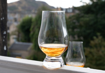 Glass of single malt scotch whisky served on old window sill in Scottisch house with view on old part of Edinburgh, Scotland, UK