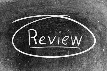 Fototapeta premium White chalk hand writing in word review on blackboard background