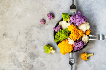Different cauliflower cabbage on plate and grey concrete background with forks. Top view with copy space