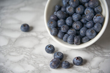A group of fresh blueberries on a white and black marble table. 