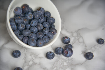 A group of fresh blueberries on a white and black marble table. 