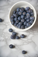 A group of fresh blueberries on a white and black marble table. 