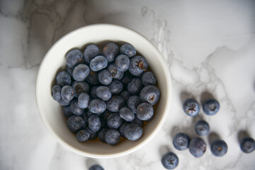 A group of fresh blueberries on a white and black marble table. 