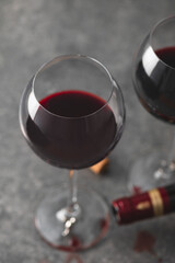 Glasses of red wine with empty bottle lying nearby and spilled drops of wine, shot from above
