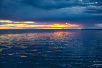 Sea pier with a lighthouse against the backdrop of the setting s
