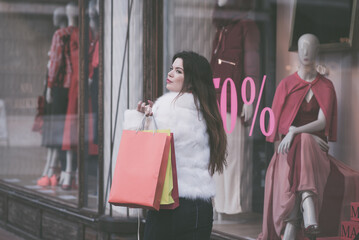 Elegantly dressed woman with shopping bags in front of shop window