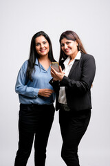 Two Young indian business woman or employee watching some detail in smartphone and discussing