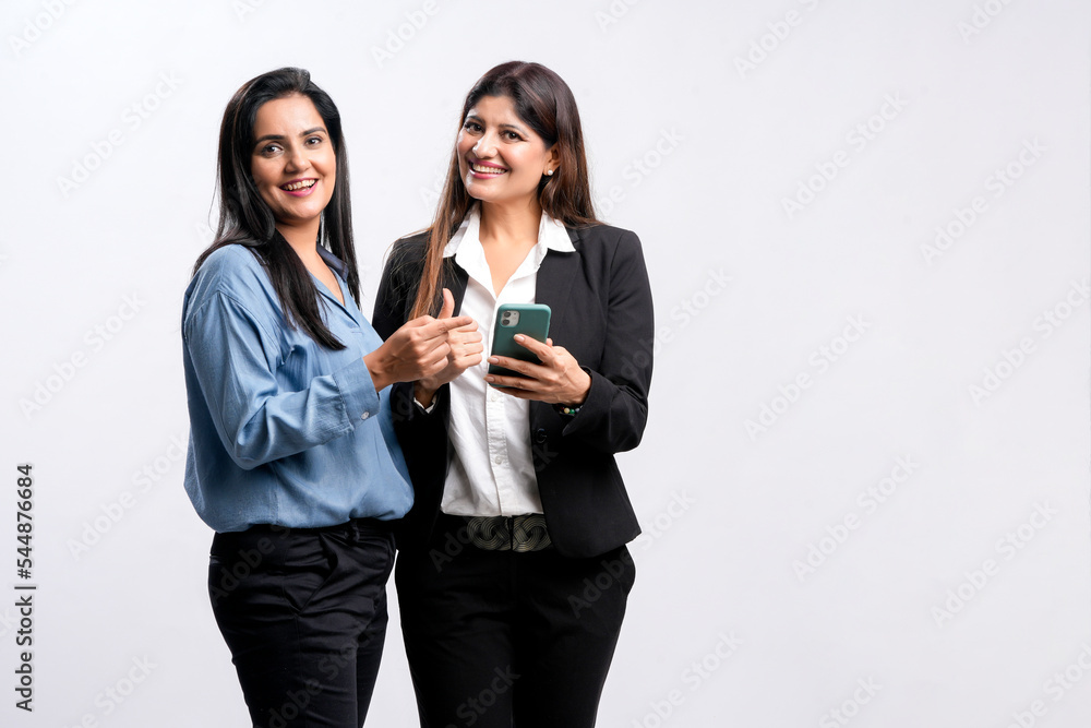 Canvas Prints Two Young indian business woman or employee watching some detail in smartphone and discussing