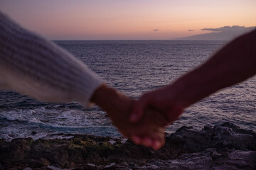 Blurry woman and man hands holding each other over the beach. Horizon over the sea sunset light