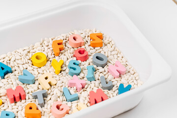 Colorful letters of the alphabet in sensory bin. Primary school or preschool, kindergarten. Educational game. Learning through play. Sensory play for toddlers.. - obrazy, fototapety, plakaty