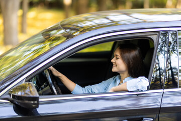 Beautiful young smiling woman driving her car.