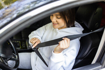 Young woman hand fastening a seat belt in the car