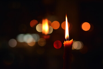 the flame of the candle is reflected in the dark glass of the window