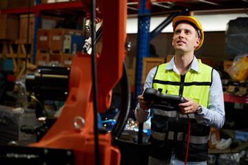 factory worker or engineer operating remote switch controller to control robot machine in the factory