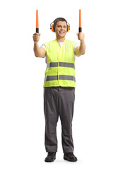 Full length pоrtrait of a male aircraft marshaller signalling with wands
