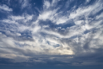 Cirrus clouds of bizarre shape are illuminated by the sun creating a natural abstraction, a landscape of the summer sky