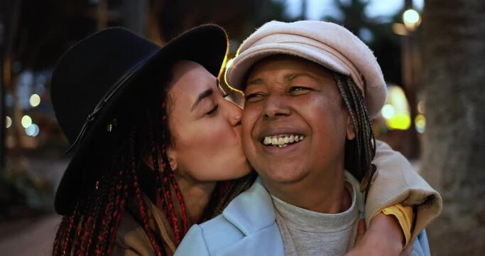 Happy african mother and daughter smiling on camera in the city - Winter and love family concept