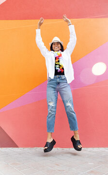woman jumping for joy on a wall with many colors
