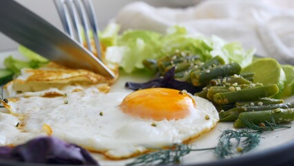 Breakfast with scrambled eggs, a knife and fork cut fried eggs for eating protein and healthy fats for breakfast, fried eggs with vegetables help you get enough for the whole day, for productive work.
