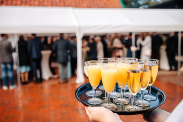 Waiter holds a tablet with many drinks. Champagne glasses and orange juice at weddings and...