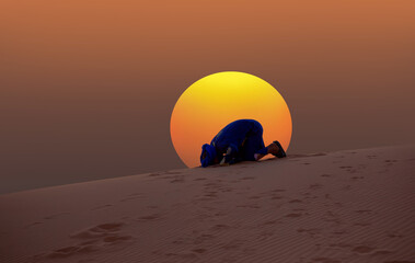 Fototapeta na wymiar Berber prays to God in the Sahara desert at amazing sunset