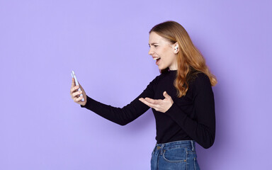 angry woman screams loudly at her phone while standing on a purple background