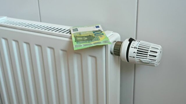 Falling euro banknotes in front of a heater
