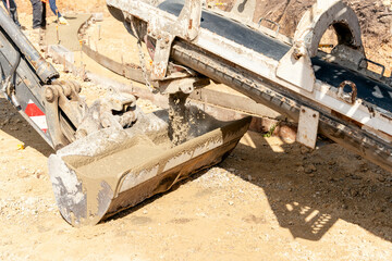 Concrete mixer truck pouring fresh wet concrete into excavators bucket at a construction site