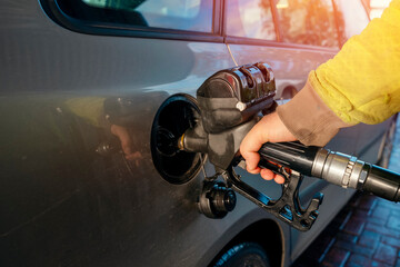 A man filling fuel tank of his car with diesel fuel at the petrol station close up, as cost of fuel going up