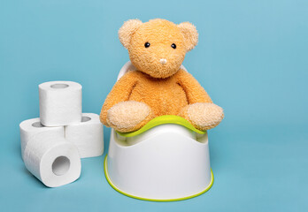 Soft toy bear on a potty on a blue background.