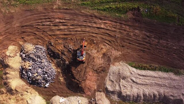 Excavator filling bucket with semi-dry concrete on construction site Aerial shot