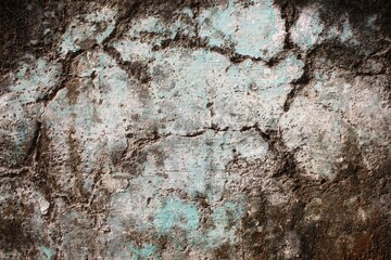A weathered concrete wall with cracks and peeling paint, showing signs of age and decay.
