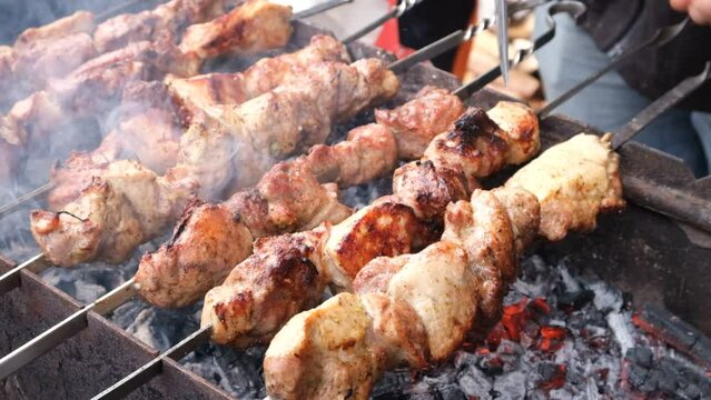 a man roasts meat on a fire. Onion and barbecue. Grilling pork neck. Roasted carrots. Fatty food, festive food of the CIS countries. May 1, working day. Non vegan food.