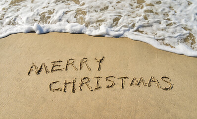 Merry Christmas handwritten in sand on a beautiful beach