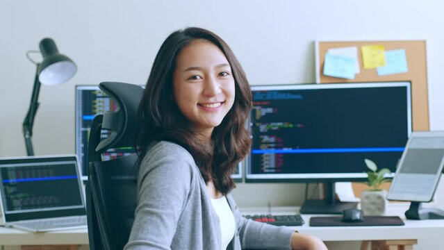 Portrait young Asian woman developer programmer, software engineer, IT support, look at camera and smile enjoy working at  office.