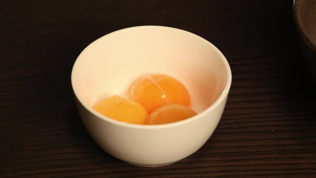 3 egg yolks close up in small white bowl