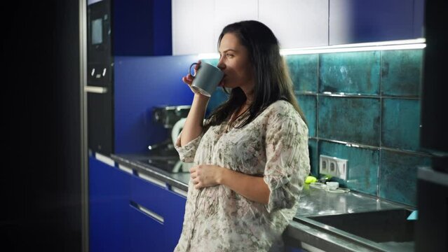 Lifestyle girl in a shirt drinking coffee from the morning wine kitchen. A woman alone at home relaxes with a cup of tea. High quality 4k footage